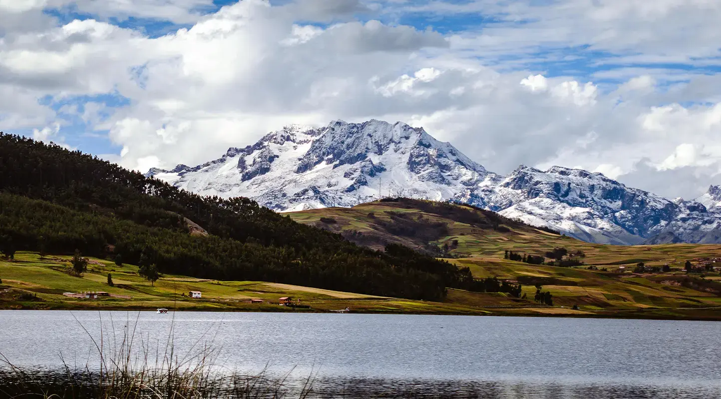 Turistas conduciendo cuatrimotos cerca de la Laguna de Huaypo con montañas de fondo en Cusco, Perú